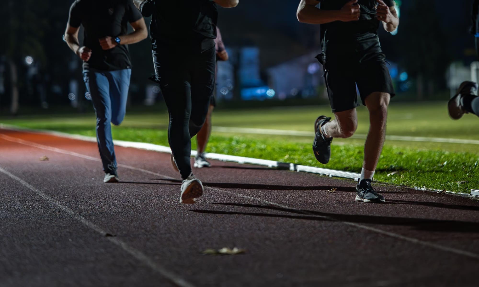 An athlete running under floodlights during an evening training session